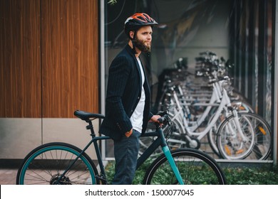 Ein junger, stylischer Hipster-Geschäftsmann, der mit dem Fahrrad auf der Stadtstraße arbeitet. Gruppe von Fahrrädern in Parkplätzen in der Stadt