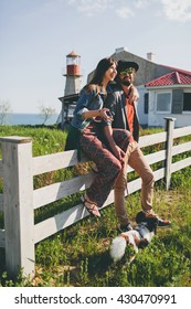 young stylish hipster couple in love walking with dog in countryside