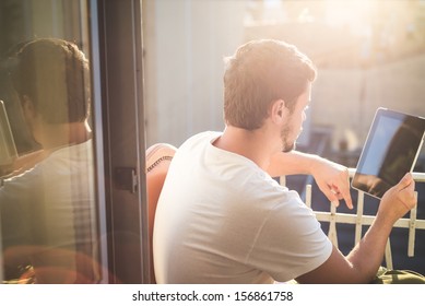 young stylish hipster man using tablet on the house balcony
