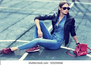 Young Stylish Hipster Woman Outdoor, Wearing Sunglasses, Black Leather Jacket, Jeans Overall, Suede Sneakers, Leather Backpack, Urban Fashion