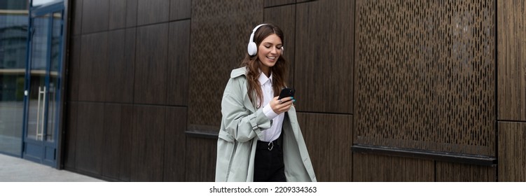 young stylish HR manager walking down the street in headphones next to the business center - Powered by Shutterstock