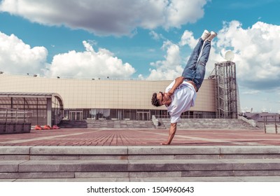 Young Stylish Man Standing One Arm, Guy Dancer, Summer City, Dancing Break Dance, Healthy Fitness Athlete's Life Style, White T-shirt Jeans. Dancing To Music. Performs In Public. Free Space For Text