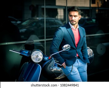 Young Stylish Man In Suit And Sunglasses Standing By His Classic Italian Scooter On Empty Road In Sunny City.