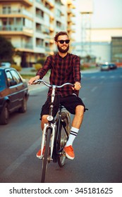 Young Stylish Man In Sunglasses Riding A Bike On City Street