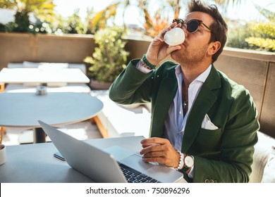 Young stylish man using laptop computer and sipping coffee - Powered by Shutterstock