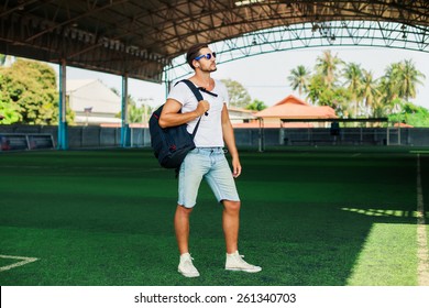 Young Stylish Men Posing On A Soccer Field,listen Music.Having Fun.Wear Cool Sportswear,big Sport Bag,denim Shorts,summer Reflecting Sunglasses,a Young Man With Beard,football Fan,Listen Music