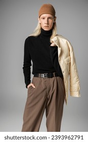 young stylish non binary model posing with winter jacket and one hand in pocket, fashion concept