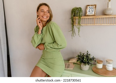 young stylish smiling woman in green summer dress in modern interior apartment home relaxing fashion style trend - Powered by Shutterstock