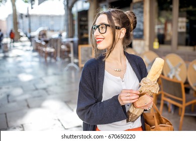 Young stylish woman buying a french baguette standing on the street in Lyon city