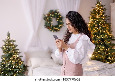 Young Stylish Woman Is Shopping Online. Christmas Call To Family. Virtual Congratulations On The Holiday. New Year Sale Lifestyle. Smartphone Chat New Technology. Together At A Distance. 