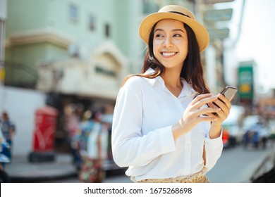 Young Stylish Woman Using Phone Walking On The Street