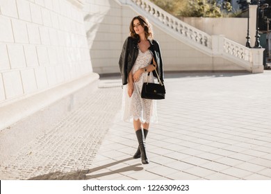 Young Stylish Woman Walking In Street In Fashionable Outfit, Holding Purse, Wearing Black Leather Jacket And White Lace Dress, Spring Autumn Style, Posing, High Leather Boots