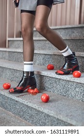 Young stylish woman wearing coat and hills walking down the stairs outdoors urban background stepping on tomatoes legs close-up