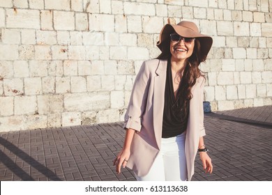 Young Stylish Woman Wearing Neutral Blazer And Hat Walking On The City Street In Spring. Casual Fashion, Elegant Look. Plus Size Model.