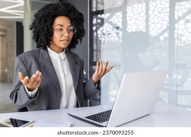 Young successful African-American businesswoman communicates via video call with clients, partners, conducts business training. Sitting in the office at the laptop. - Powered by Shutterstock