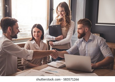 Young Successful Business People Are Working In Office. Two Men Are Shaking Hands