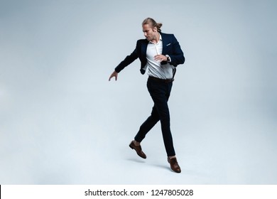 Young successful businessman in suit rejoicing, jumping over white background