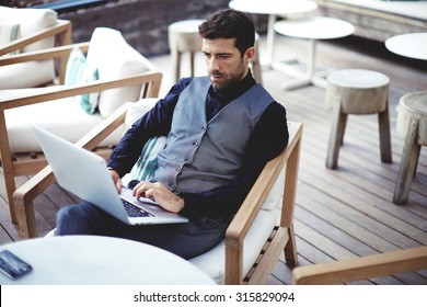 Young successful businessman working on a laptop while sitting in cafe during work break lunch,thoughtful entrepreneur connecting to wireless via computer, intelligent male freelancer work on net-book