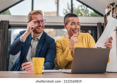 Young successful diverse couple sitting in living room or kitchen discussing new home project using laptop working and planing calculating home finances doing paperwork happy smiling laughing