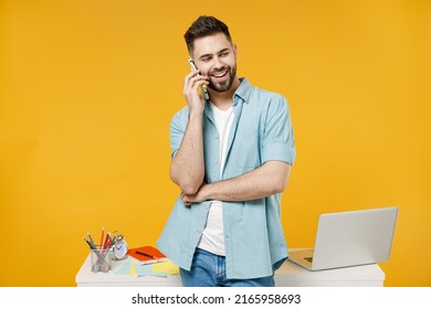 Young successful employee business man in shirt stand work at white office desk with pc laptop talk on mobile cell phone conducting pleasant conversation isolated on yellow background studio portrait - Shutterstock ID 2165958693