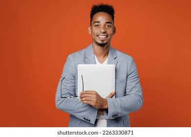 Young successful employee IT business man corporate lawyer wearing classic formal grey suit shirt work in office hold closed laptop pc computer glasses isolated on plain red orange background studio - Shutterstock ID 2263330871