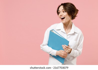 Young successful employee business secretary woman corporate lawyer in classic white shirt work in office hold blue folder for papers document bookkeeping look aside isolated on pastel pink background
