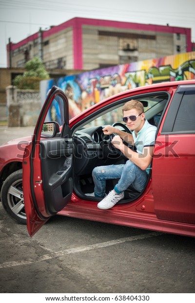Young successful guy sits in the car. Young\
businessman in his car. Style of life of a young man. The guy in\
the sunglasses is sitting in the\
car.
