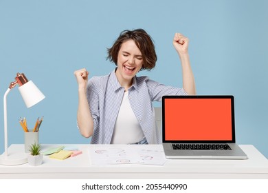 Young successful happy employee business woman in casual shirt sit work at office desk with pc laptop computer blank screen workspace area do winner gesture isolated on pastel blue background studio