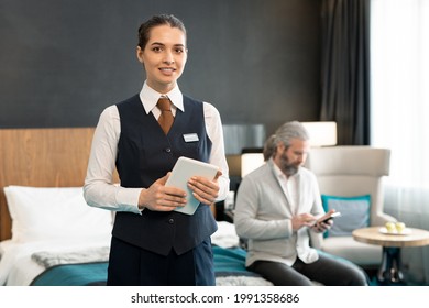 Young Successful Hotel Manager With Touchpad Standing Against Mature Male Client