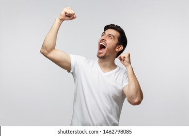 Young Successful Man Screaming Yes And Raising Clenched Fist Isolated On Gray Background. People, Success, Winning And Celebration Concept