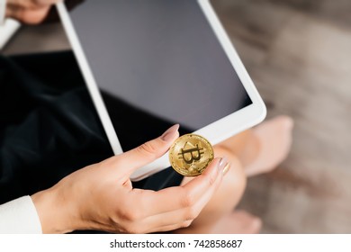 a young successful modern girl with glasses is holding a gold bitcoin and a tablet in her hands - Shutterstock ID 742858687