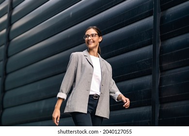 A young, successful, and smiling businesswoman dressed smart casual walking outdoors. The woman is going on the path of success. - Powered by Shutterstock