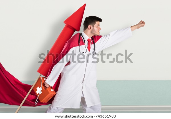 Young Superhero Doctor Carrying First Aid Box\
While Flying On Rocket
