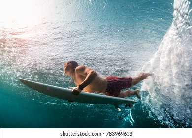 Young surfer dives under the ocean wave and performs trick named in surfing as a Duck Dive