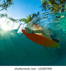 Young Surfer Paddling Through The Ocean