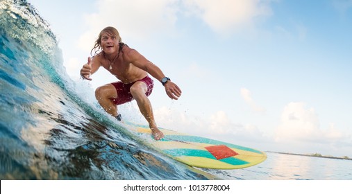 Young surfer rides ocean wave and shows the Shaka sign. Extreme sport and active lifestyle concept - Powered by Shutterstock