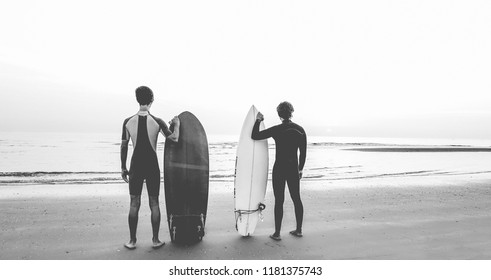 Young surfers waiting the waves on the beach - Sport friends getting ready for surfing - Extreme sport, youth lifestyle and recreation concept - Black and white editing