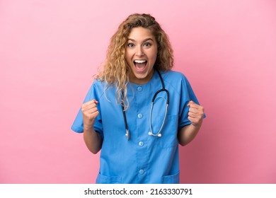Young surgeon doctor woman isolated on pink background celebrating a victory in winner position