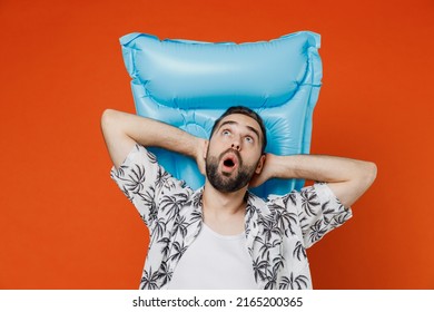 Young Surprised Amazed Tourist Man Wear Beach Shirt Lies On Inflatable Mattress Hotel Pool Look Overhead Isolated On Plain Orange Background Studio Portrait. Summer Vacation Sea Rest Sun Tan Concept