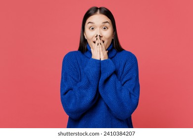 Young surprised astonished shocked woman of Asian ethnicity she wearing blue sweater casual clothes cover mouth with hands isolated on plain pastel pink background studio portrait. Lifestyle concept