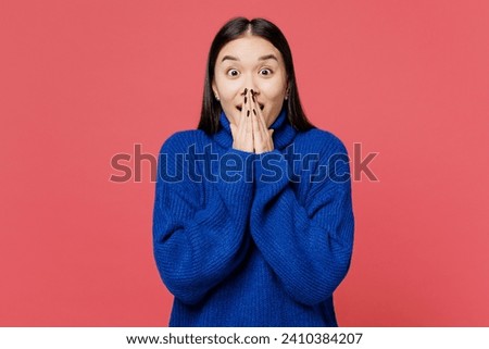Young surprised astonished shocked woman of Asian ethnicity she wearing blue sweater casual clothes cover mouth with hands isolated on plain pastel pink background studio portrait. Lifestyle concept