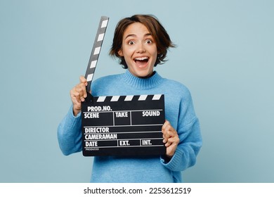 Young surprised caucasian woman wear knitted sweater hold in hand classic black film making clapperboard isolated on plain pastel light blue cyan background studio portrait. People lifestyle concept - Shutterstock ID 2253612519
