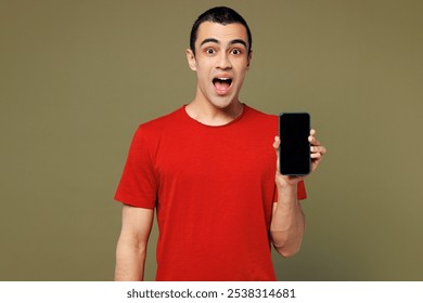 Young surprised middle eastern man he wear red t-shirt casual clothes hold in hand use mobile cell phone with blank screen workspace area isolated on plain pastel green background. Lifestyle concept - Powered by Shutterstock