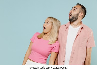 Young surprised shocked amazed fun couple two friends family man woman in casual clothes looking aside on workspace area together isolated on pastel plain light blue color background studio portrait