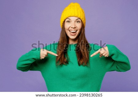 Young surprised shocked excited woman she wear green sweater yellow hat casual clothes point index finger on herself isolated on plain pastel light purple background studio portrait. Lifestyle concept