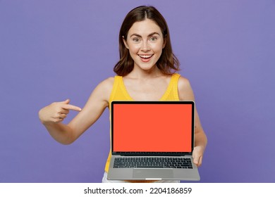 Young Surprised Shocked Woman 20s She Wear Yellow Tank Shirt Hold Use Work Point Index Finger On Laptop Pc Computer With Blank Screen Workspace Area Isolated On Plain Pastel Light Purple Background