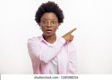 Young surprised woman in stylish outfit pointing her finger sideways. shocked young black female showing white wall, isolated background, copy space - Shutterstock ID 1185588256