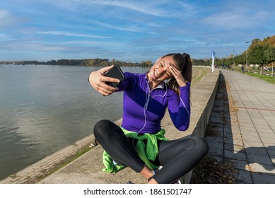 Young Sweaty Active Fitness Athlete Woman Taking A Break After Outdoor Training And Taking A Selfie With Her Smartphone For Social Media To Show Her Success Of Running And Jogging Exercises