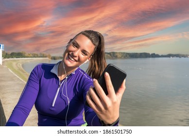 Young Sweaty Active Fitness Athlete Woman Taking A Break After Outdoor Training And Taking A Selfie With Her Smartphone For Social Media To Show Her Success Of Running And Jogging Exercises