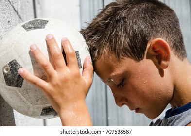 A Young Sweaty Soccer Player Leans His Forehead To The Ball